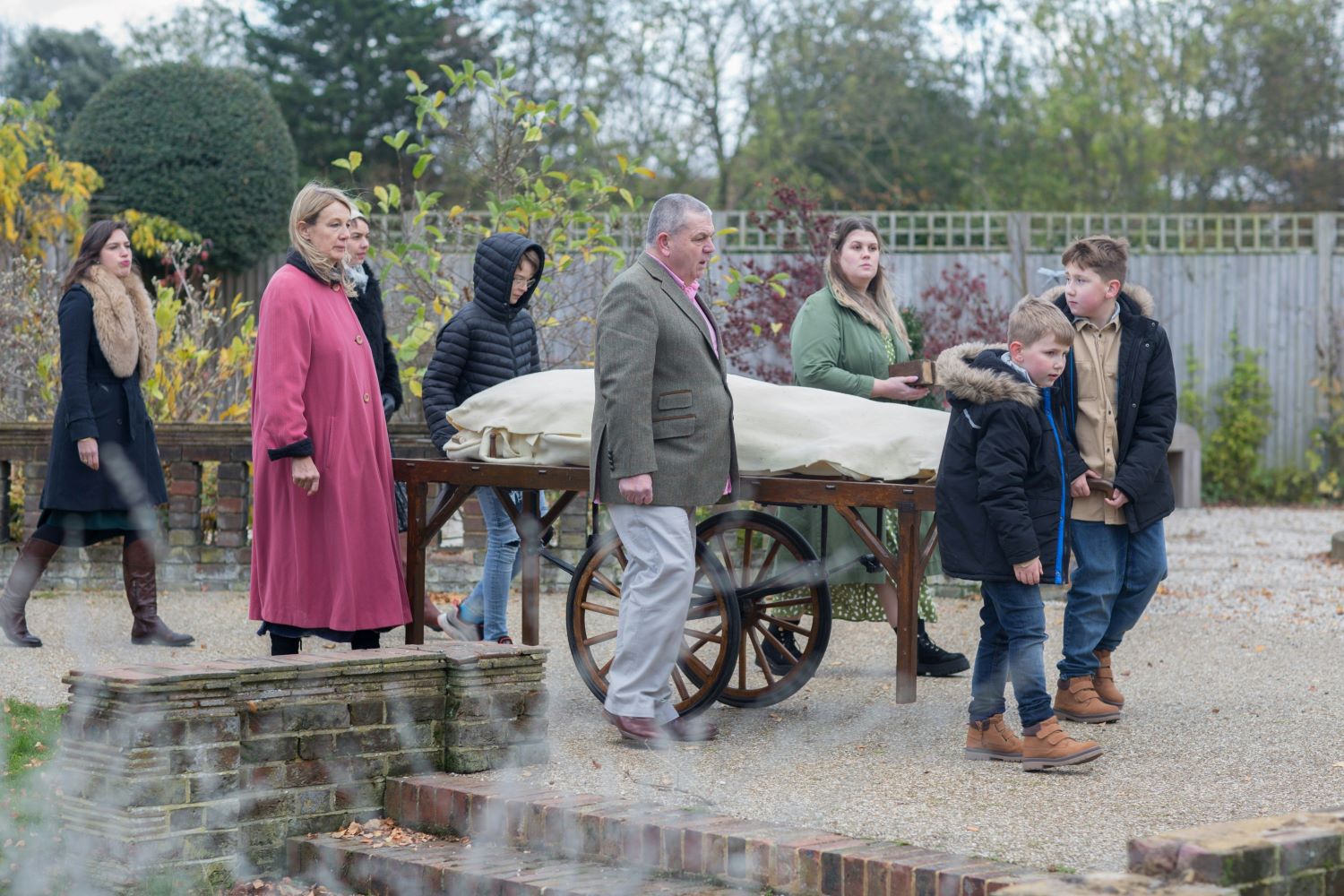 A group of people accompany a shrouded human body during a green burial procession.