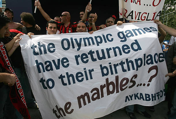 Protestors at the 2007 Athens Olympics hold a sign saying "The Olympic games have returned to their birthplace. What about the marbles?"